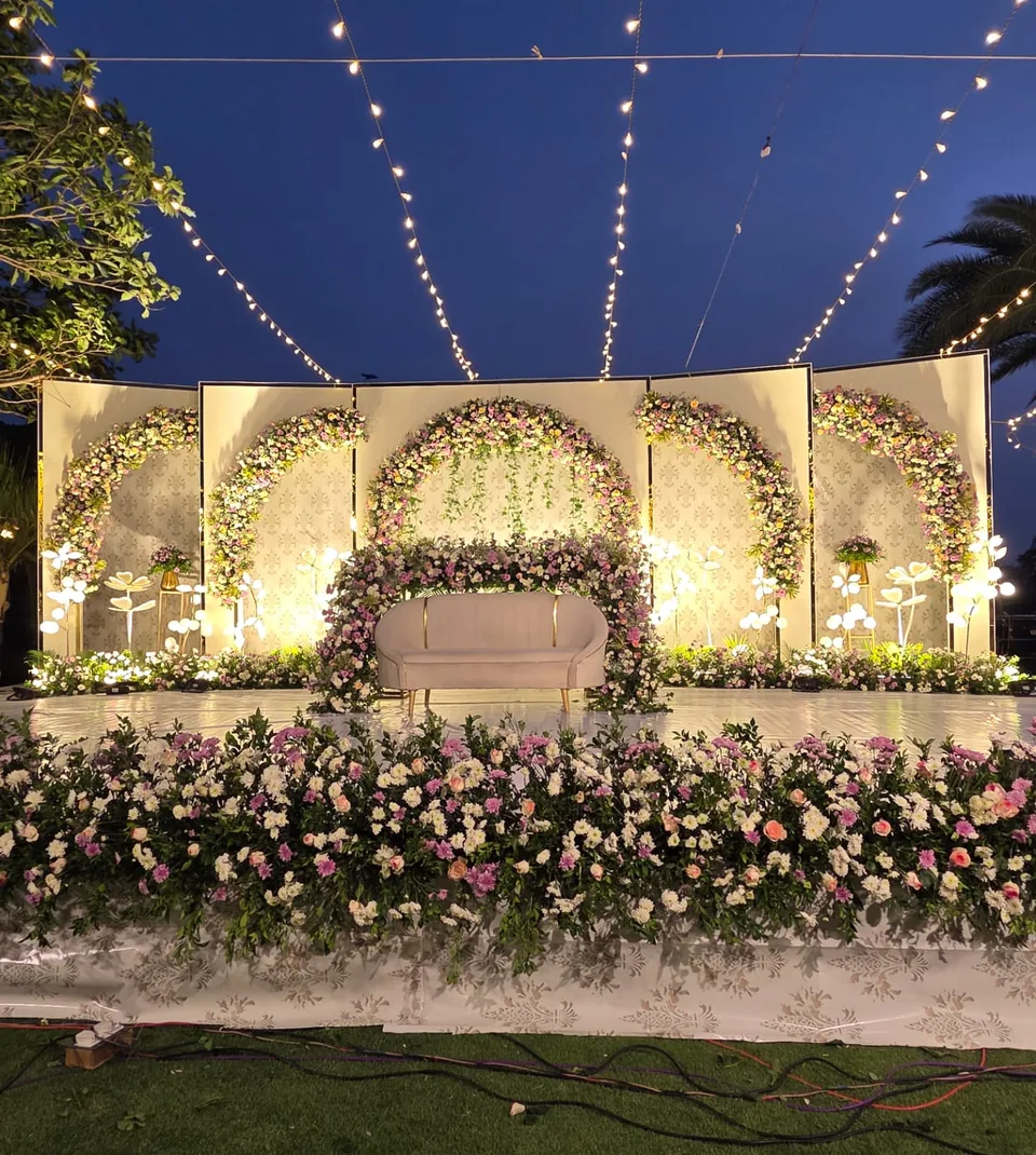 Outdoor evening setup with string lights and ivory floral arch