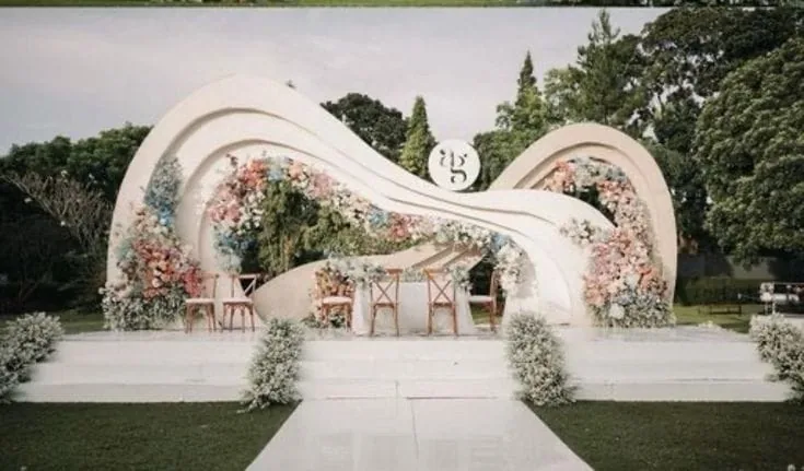 Sculptural outdoor arches with white florals on open lawn