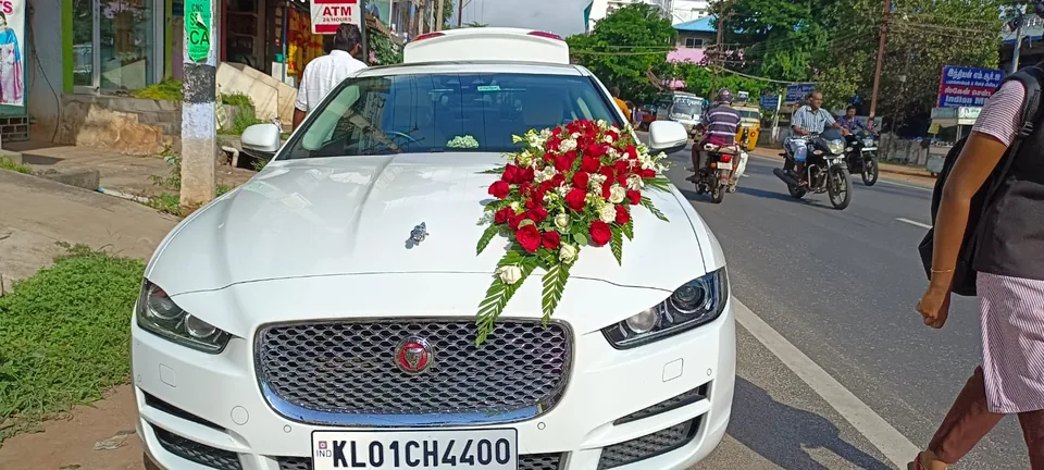 White wedding car styled with a rose and orchid bonnet arrangement
